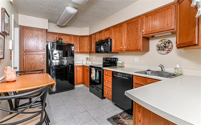 a kitchen with stainless steel appliances granite countertop a refrigerator a sink dishwasher a stove and chairs with wooden floor