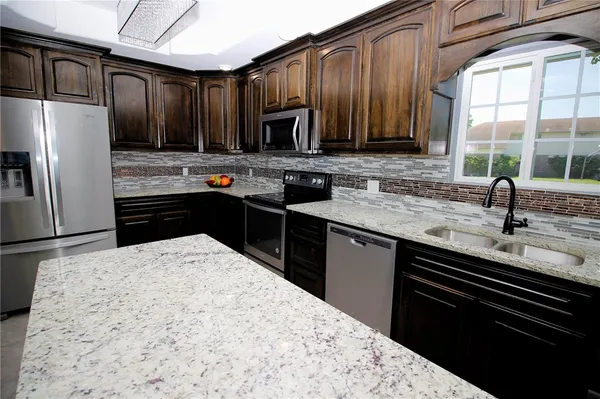 a kitchen with stainless steel appliances kitchen island granite countertop a sink stove and refrigerator