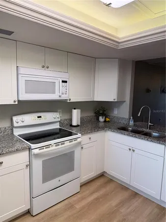a kitchen with granite countertop white cabinets and white appliances