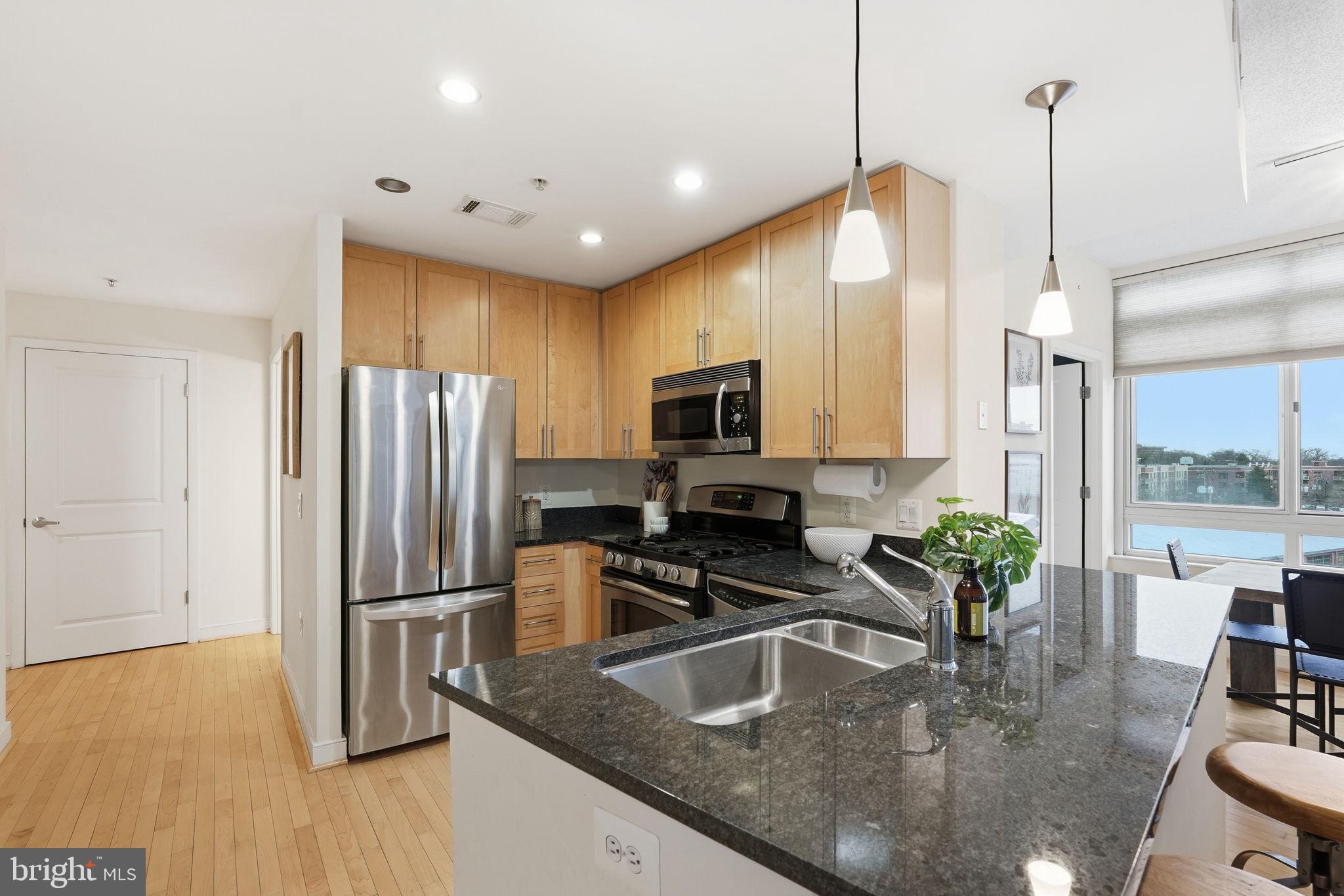 820 North Pollard Street, Unit 504 Arlington, VA 22203 - Photo 2 of 27 a kitchen with stainless steel appliances granite countertop a sink a stove and a wooden floors
