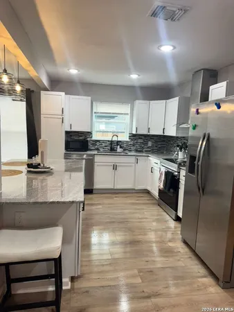 a kitchen with stainless steel appliances granite countertop a table chairs sink and cabinets