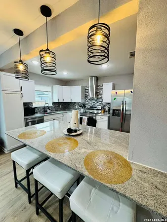 a kitchen with stainless steel appliances granite countertop a sink a stove and a wooden floors