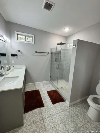 a bathroom with a sink a toilet a mirror and shower
