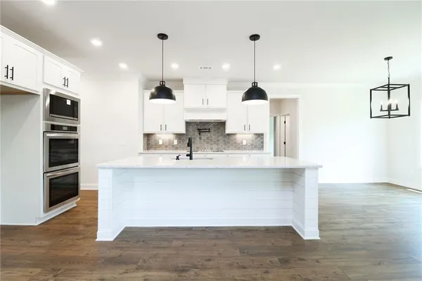 a large kitchen with stainless steel appliances a large counter top a sink a stove and a refrigerator
