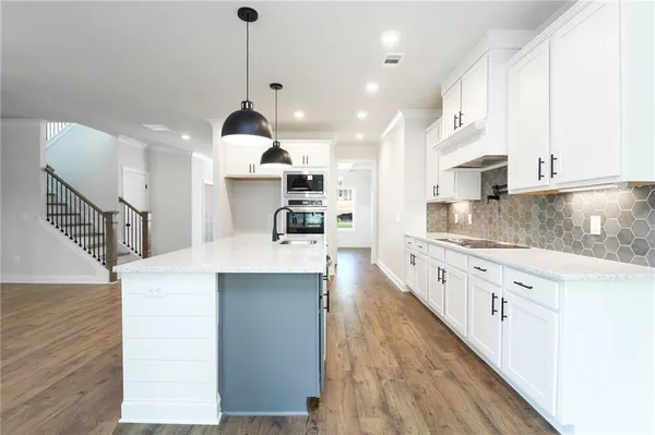 a large kitchen with kitchen island a stove a sink a center island and wooden floor