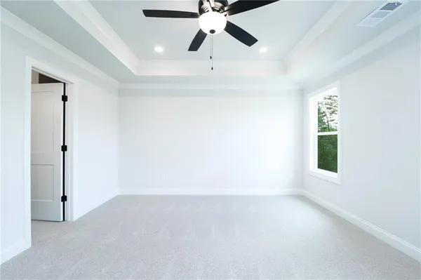 an empty room with chandelier fan and windows