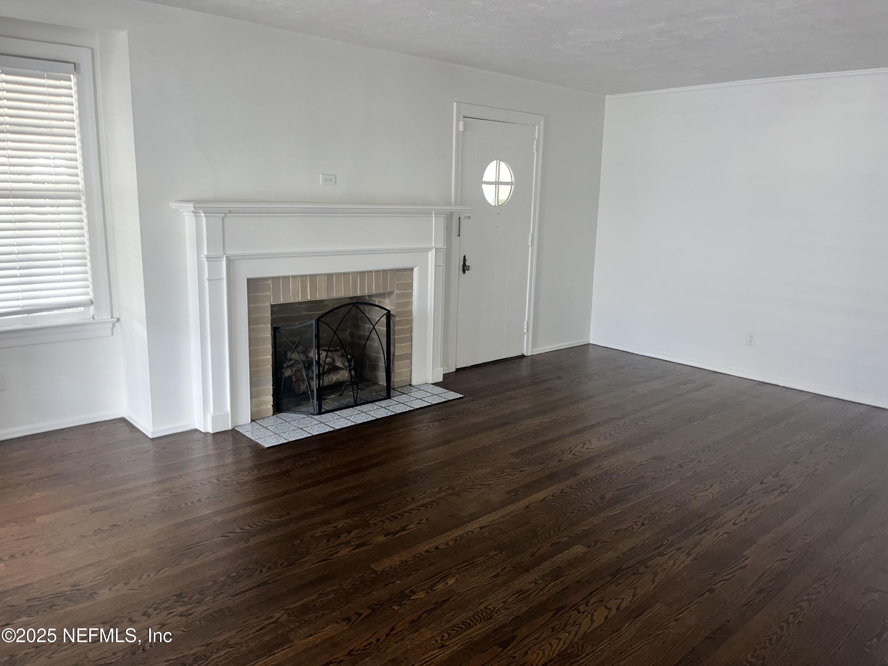 1802 Kingswood Road Jacksonville, FL 32207 - Photo 2 of 13 an empty room with wooden floor fireplace and windows