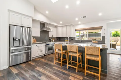 a kitchen with granite countertop a refrigerator and white cabinets