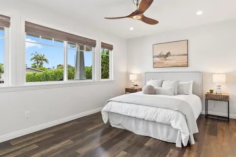 a bedroom with a bed painting on wall and a large window
