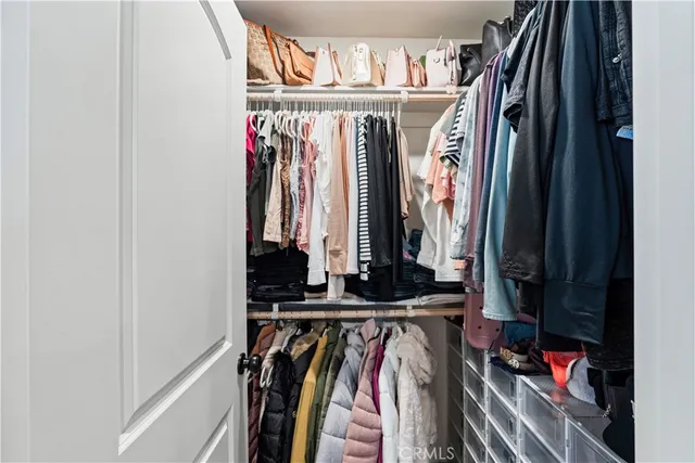 a view of walk in closet with clothes and shoes