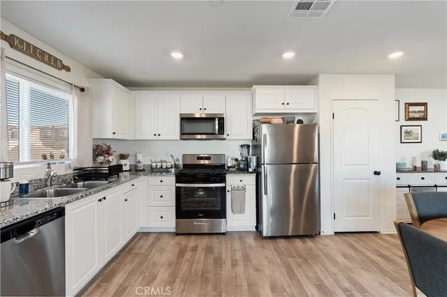 a kitchen with a refrigerator a sink dishwasher a stove top oven a refrigerator with grey cabinets and wooden floor