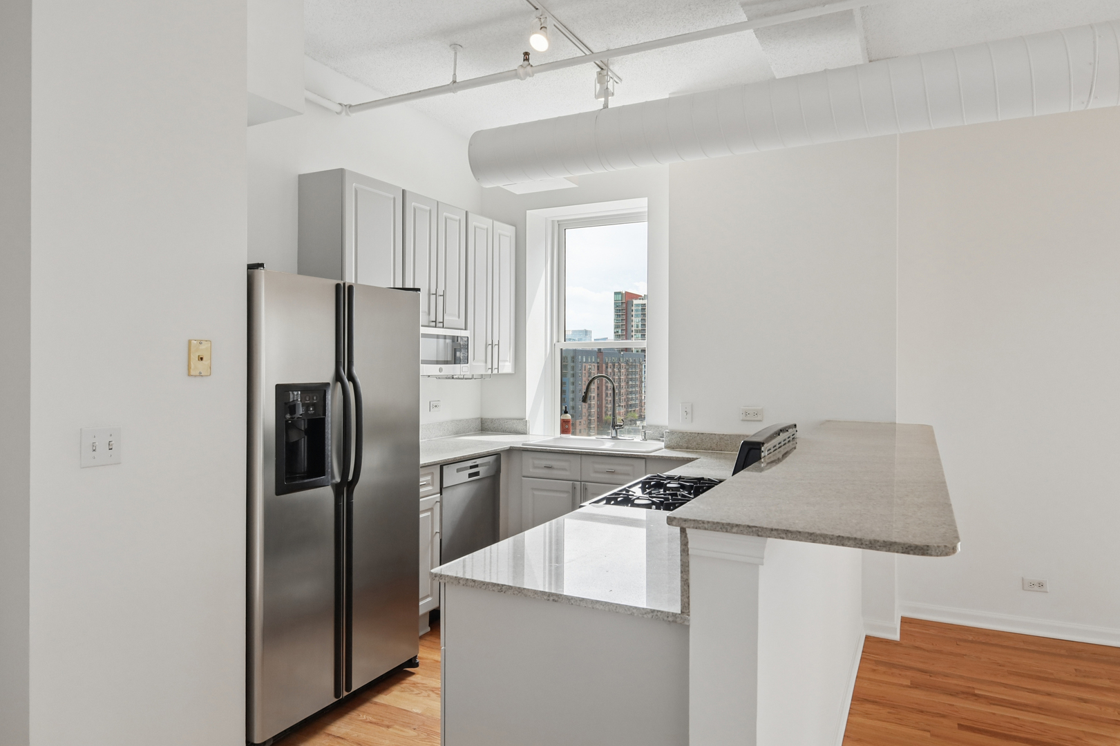 161 West Harrison Street, Unit 1007 Chicago, IL 60605 - Photo 14 of 35 a kitchen with stainless steel appliances granite countertop a refrigerator a sink a stove and a refrigerator with wooden floor