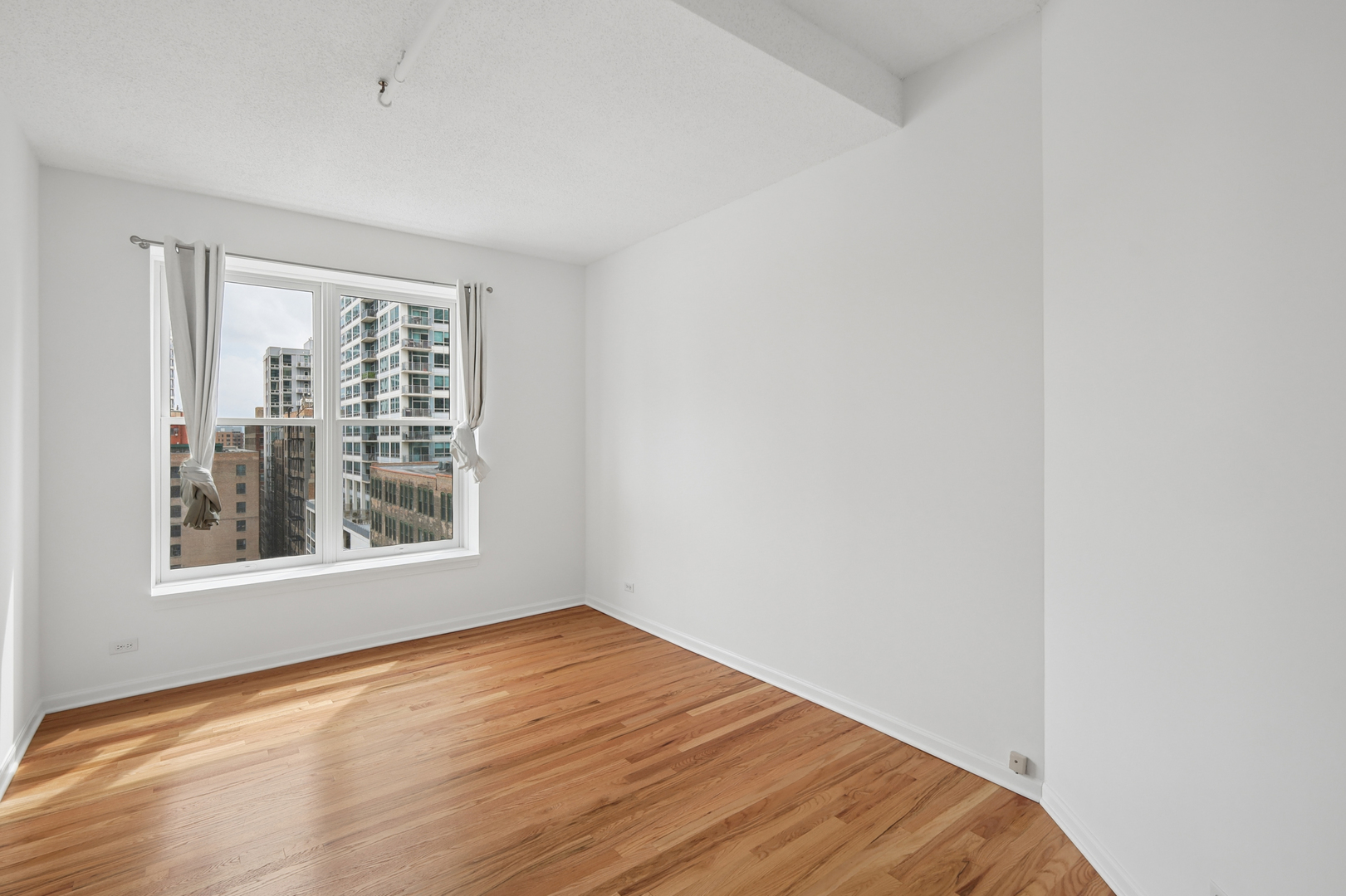 161 West Harrison Street, Unit 1007 Chicago, IL 60605 - Photo 23 of 35 a view of an empty room with wooden floor and a window