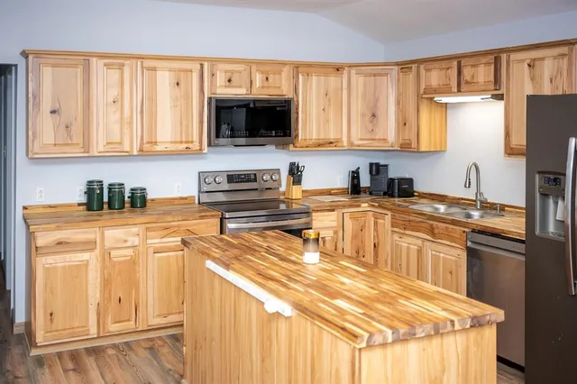 a kitchen with stainless steel appliances granite countertop a sink a stove and a refrigerator