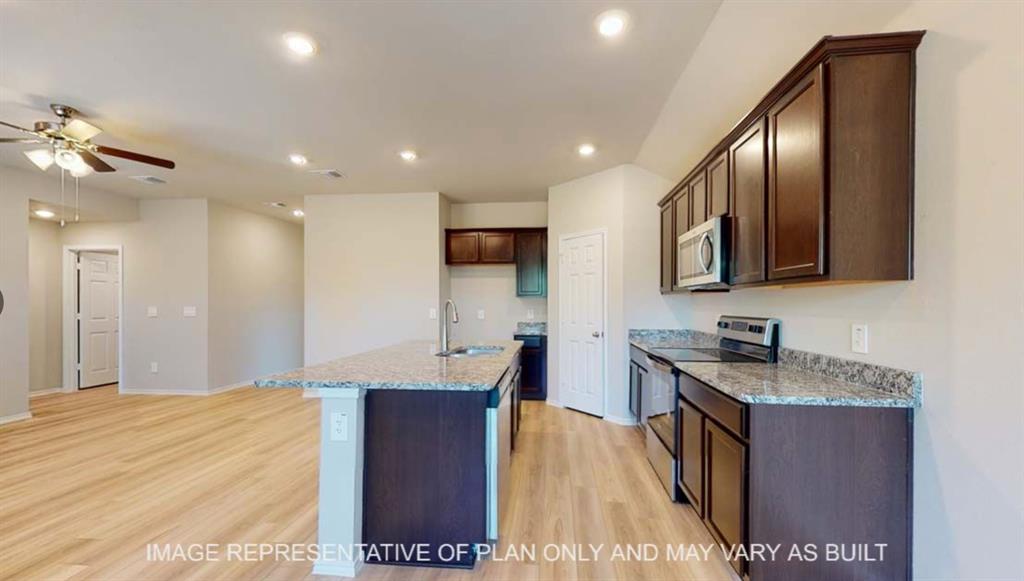 10429 Neptune Court Waco, TX 76708 - Photo 5 of 16 Spacious kitchen featuring dark wood cabinetry, light-toned countertops, stainless steel appliances, a center island with sink, and wood-finish flooring