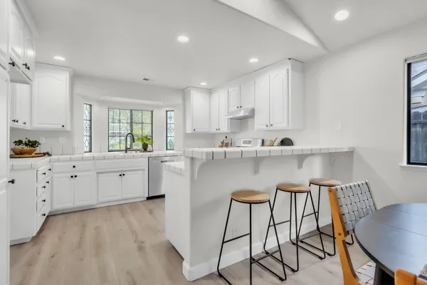 a kitchen with kitchen island granite countertop a sink a stove a dining table and chairs