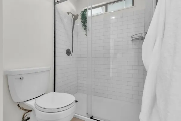 a white toilet sitting next to a shower