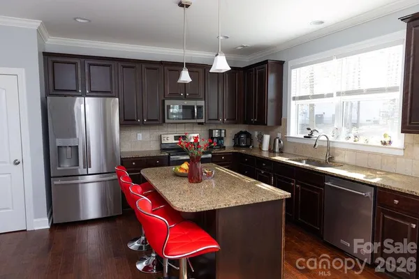a kitchen with stainless steel appliances granite countertop a sink refrigerator and a window