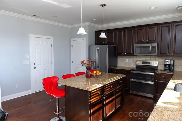 a kitchen with stainless steel appliances granite countertop a stove refrigerator and a dining table