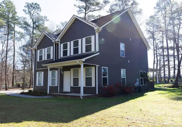 a view of a yard in front of a brick house with a large tree