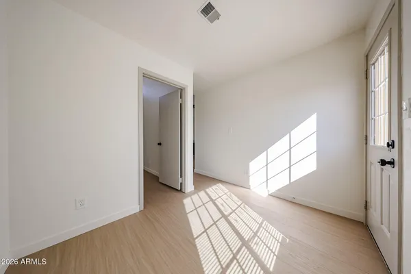 a view of empty room with wooden floor and fan
