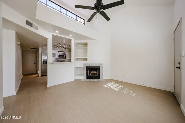 a view of a livingroom with a fireplace a ceiling fan and wooden floor