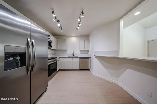 a large kitchen with stainless steel appliances kitchen island a large counter top a stove a chimney a sink and a refrigerator