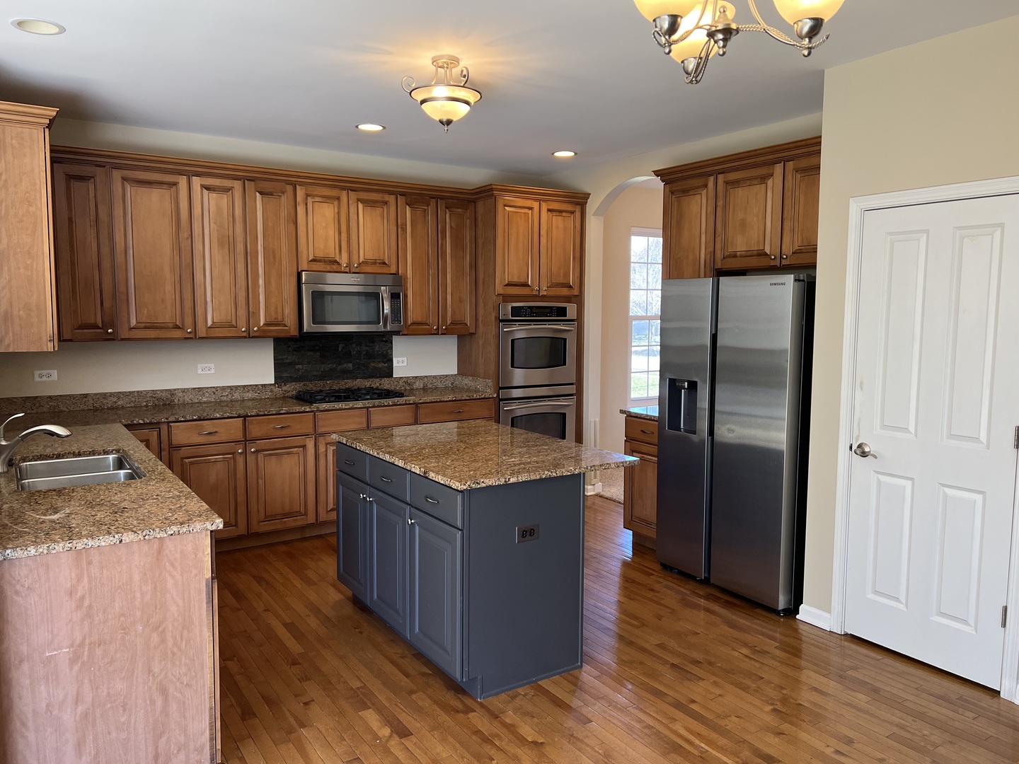 26112 Mapleview Drive Plainfield, IL 60585 - Photo 4 of 28 a kitchen with stainless steel appliances granite countertop a refrigerator a stove top oven a sink and dishwasher with wooden floor