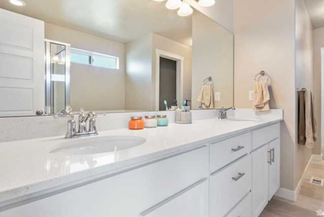 1295 East Granite Peak Road Eagle Mountain, UT 84005 - Photo 20 of 35 Dual vanity featuring white cabinetry with brushed nickel hardware, integrated sinks, a light-colored countertop, and an expansive wall mirror