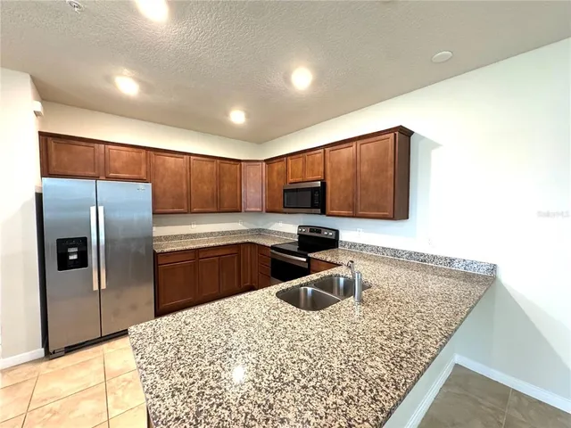 a kitchen with stainless steel appliances granite countertop a sink refrigerator and microwave