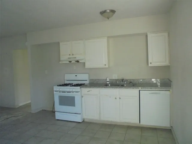 a kitchen with granite countertop white cabinets and a stove