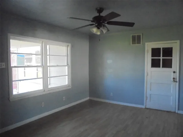 an empty room with a window and a fan