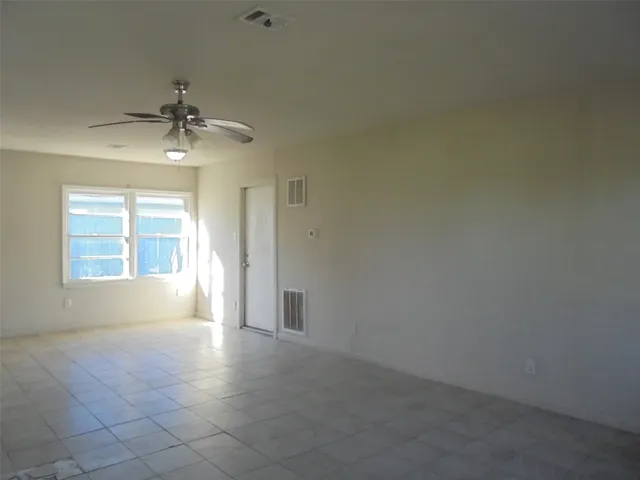 an empty room with windows and chandelier fan