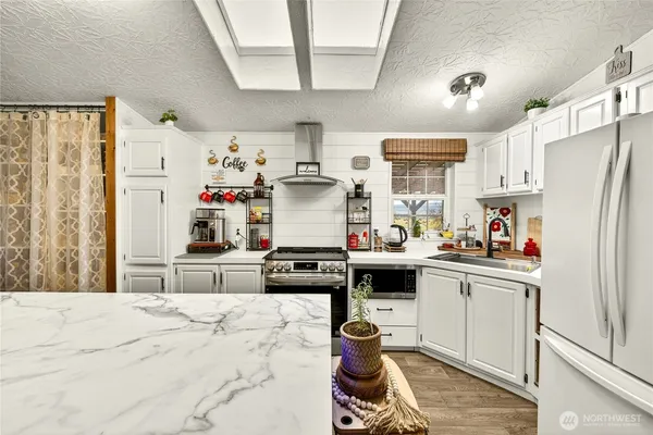 a kitchen with refrigerator a stove a sink dishwasher and white cabinets with wooden floor