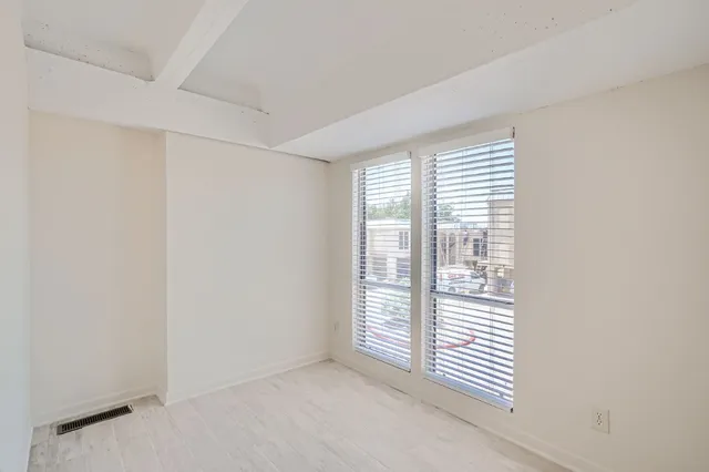 an empty room with windows and fan