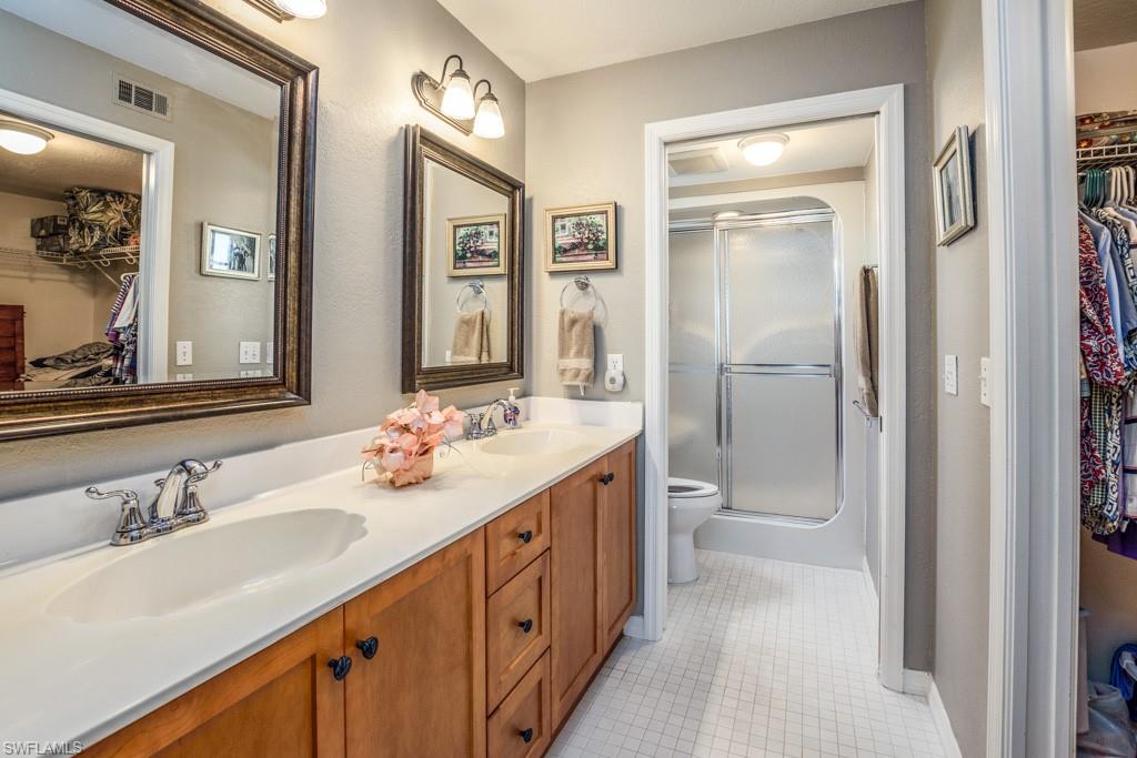 379 Gabriel Circle, Unit 2301 Naples, FL 34104 - Photo 17 of 33 a bathroom with a double vanity sink toilet and mirror