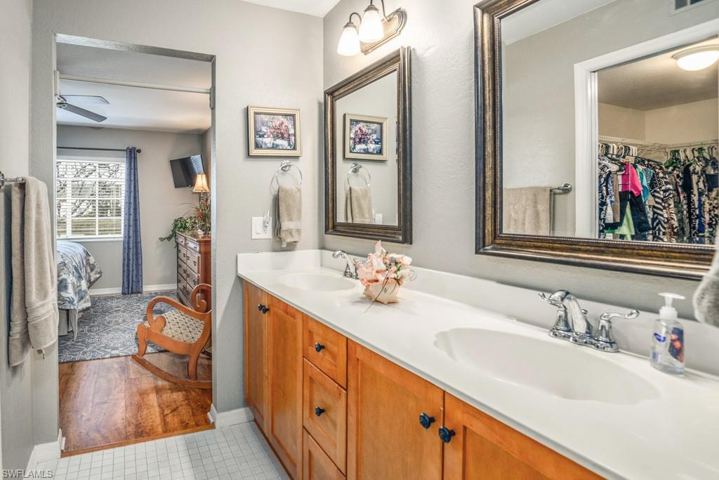 379 Gabriel Circle, Unit 2301 Naples, FL 34104 - Photo 18 of 33 a en suite bathroom with double vanity sinks a mirror and a shower