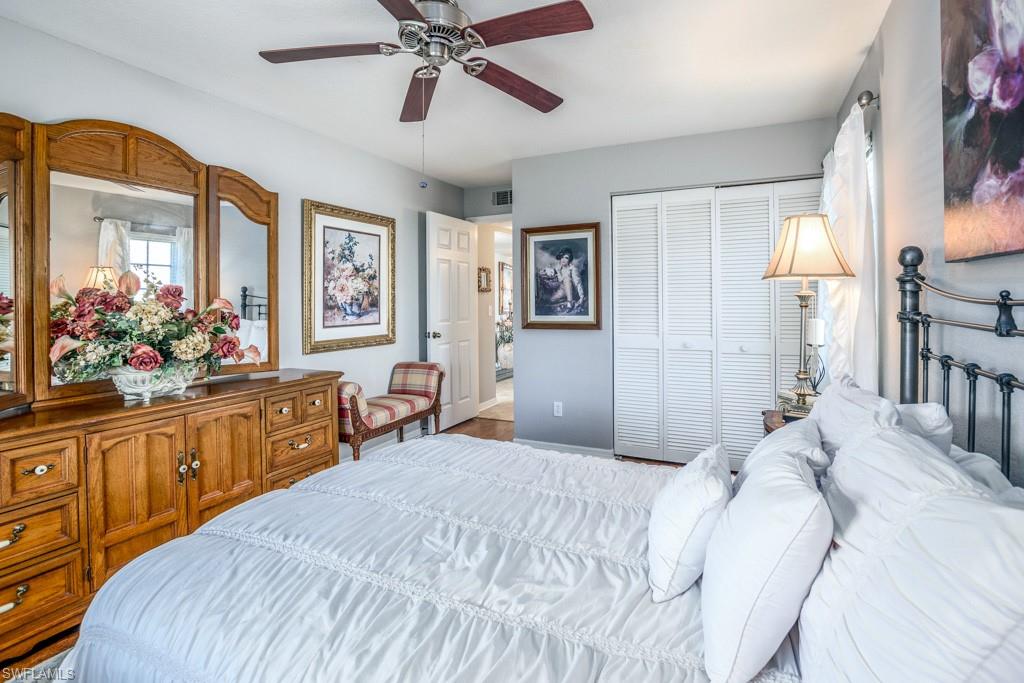 379 Gabriel Circle, Unit 2301 Naples, FL 34104 - Photo 20 of 33 a bedroom with a large bed and a chandelier