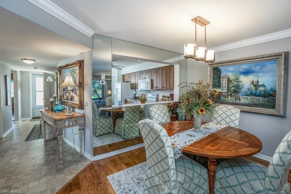 379 Gabriel Circle, Unit 2301 Naples, FL 34104 - Photo 8 of 33 a living room with furniture a chandelier and a dining table