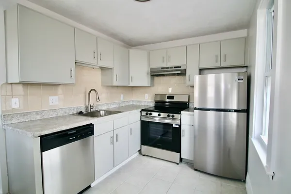 a kitchen with white cabinets and refrigerator
