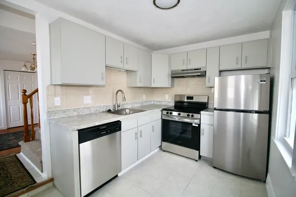 a kitchen with stainless steel appliances granite countertop a refrigerator a stove a sink and white cabinets