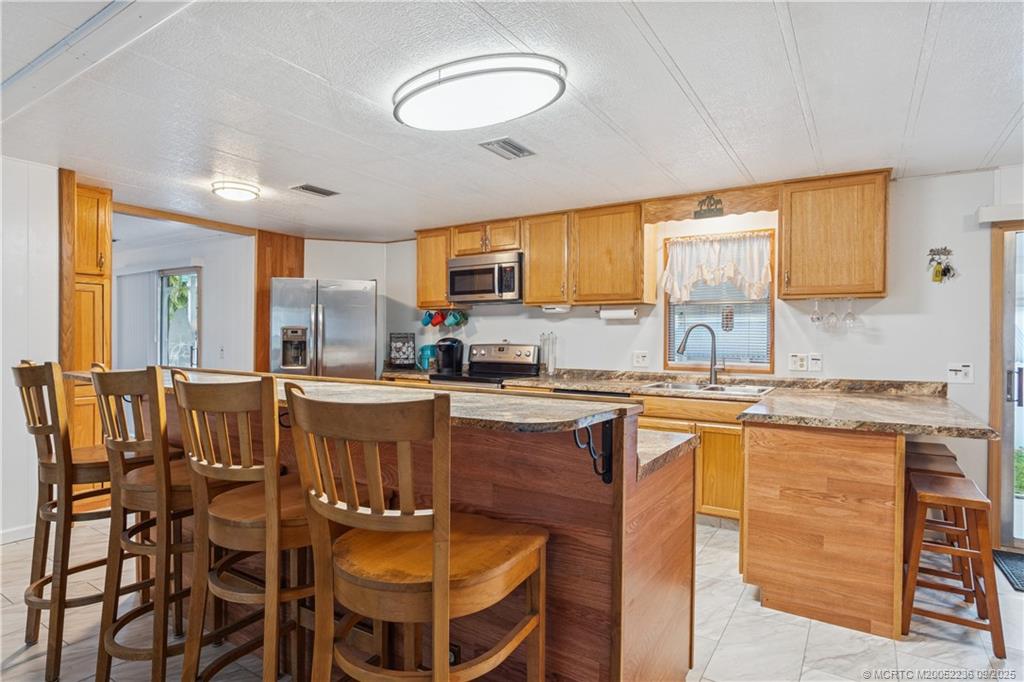 4800 Southeast Federal Highway, Unit 72 Stuart, FL 34997 - Photo 14 of 22 a kitchen with stainless steel appliances granite countertop a stove a sink a refrigerator white cabinets and wooden floor