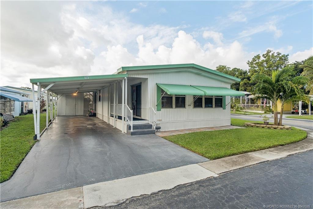 4800 Southeast Federal Highway, Unit 72 Stuart, FL 34997 - Photo 3 of 22 a view of a white house with a yard and table and chairs under an umbrella