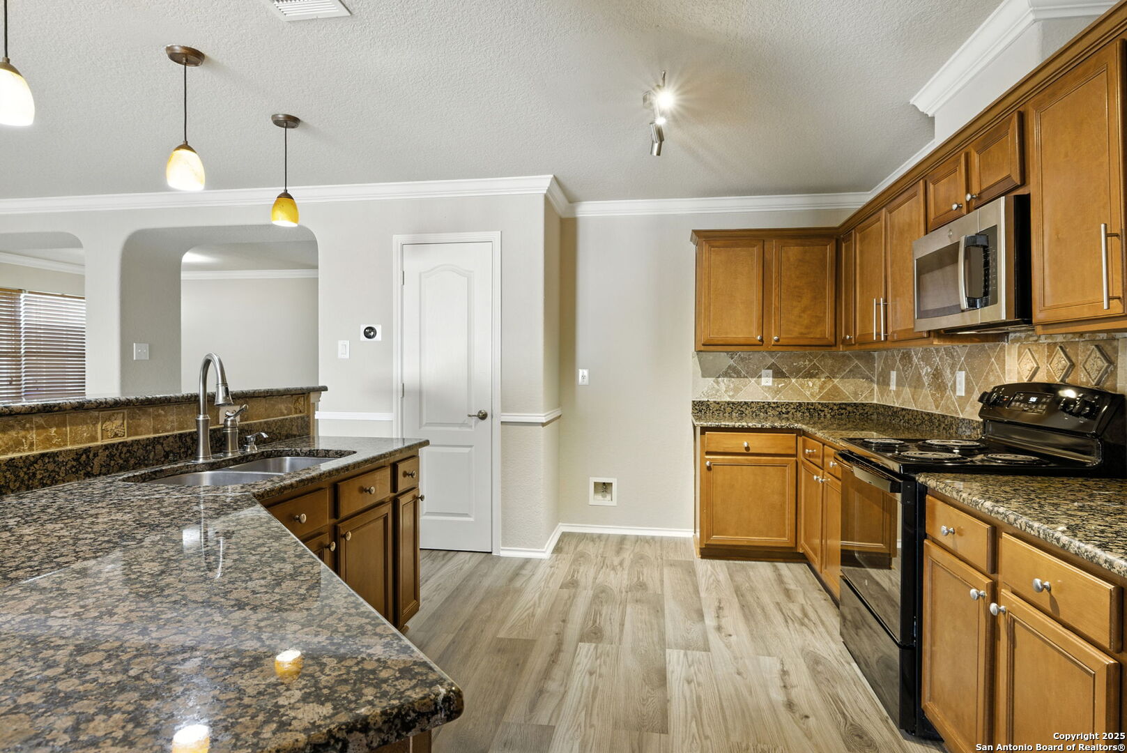 506 Leafy Ridge San Antonio, TX 78251 - Photo 22 of 48 a large kitchen with stainless steel appliances granite countertop a stove a sink dishwasher and a refrigerator with wooden floor
