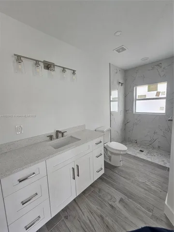 a bathroom with a granite countertop sink a toilet and bathtub