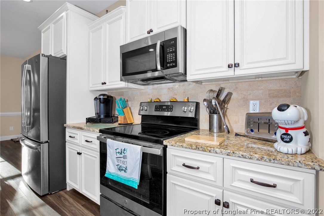 2624 Riddle Farm Road Hope Mills, NC 28348 - Photo 14 of 33 a kitchen with granite countertop stainless steel appliances a stove refrigerator and cabinets