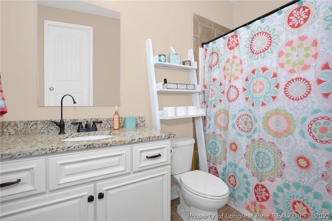 2624 Riddle Farm Road Hope Mills, NC 28348 - Photo 21 of 33 a bathroom with a granite countertop bathtub sink vanity mirror and toilet