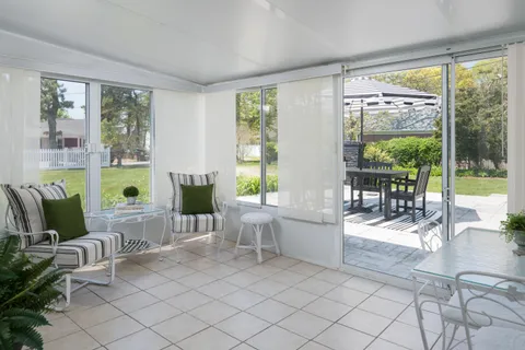 a living room with furniture large windows and wooden floor
