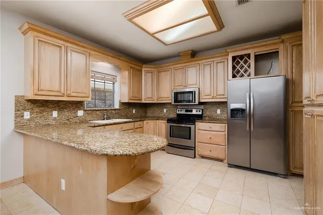 a kitchen with stainless steel appliances granite countertop a sink stove refrigerator and microwave
