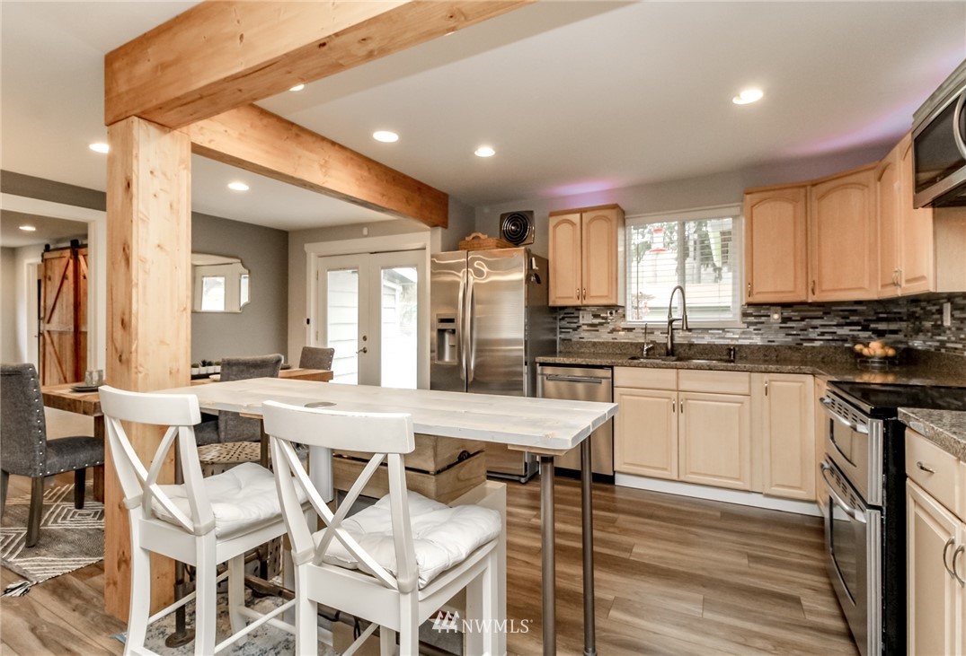 17021 Southeast Jones Road Renton, WA 98058 - Photo 8 of 27 a kitchen with stainless steel appliances granite countertop a stove top oven a sink dishwasher and white cabinets with wooden floor